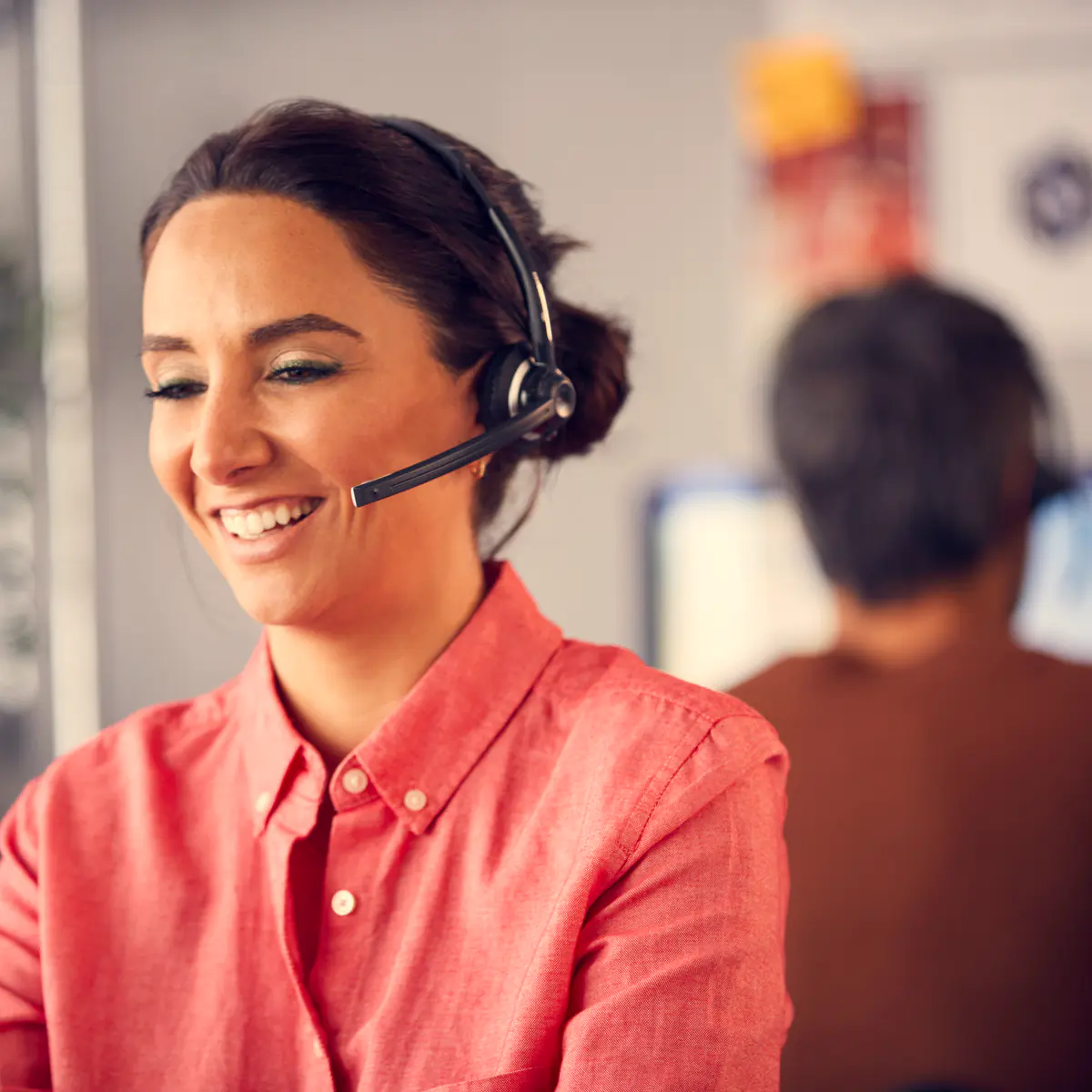 A smiling support agent with a headset helping a customer